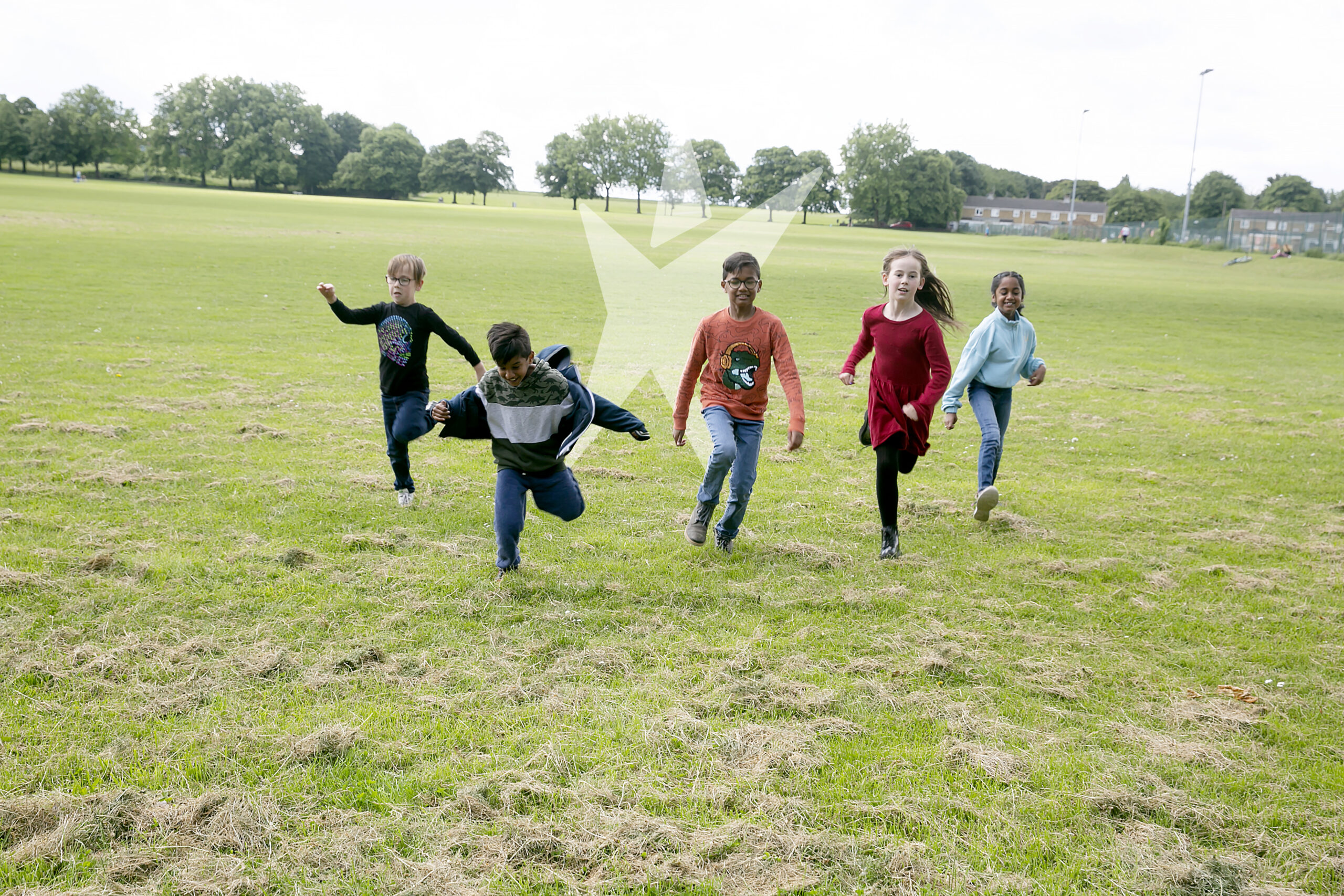A group of children in a field, running and playing.